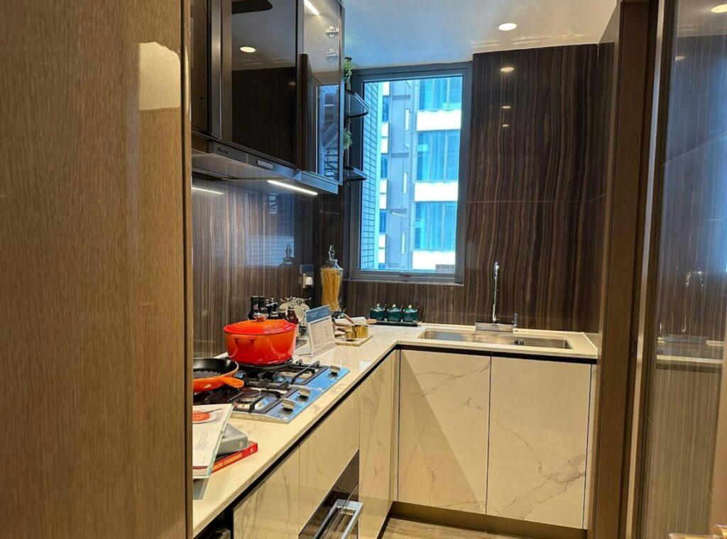 維港‧灣畔第1B期 Victoria Voyage Phase 1B 現代化廚房採用L型工作枱，配備多個吊櫃及明亮窗戶提升光線。