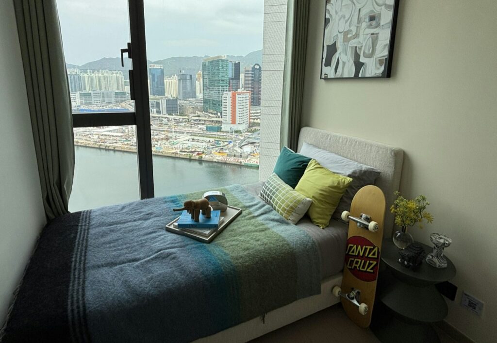啟德海灣2 Kt Marina 2 精緻次臥房設計，單人床配抱枕與滑板裝飾，窗外開揚海景及城市景觀